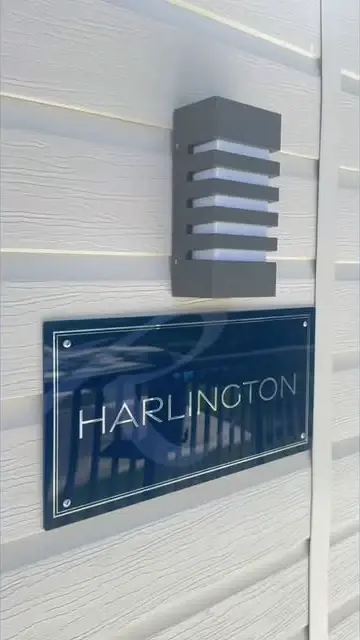 The Harlington nameplate on the lodge's pale cladding, below an outside light.
